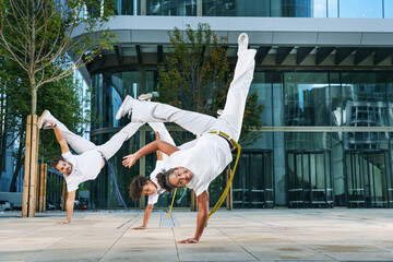 A group of sporty people of different ages training capoeira in a big city