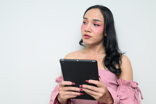 Portrait of a young Thai transgender person against white background with digital tablet computer