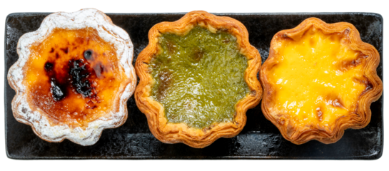 A trio of delicious tarts classic, vibrant green tea, and a rich custard Egg tart isolated on white background, Egg tart in black tray on white With clipping path, High resolution photography PNG File