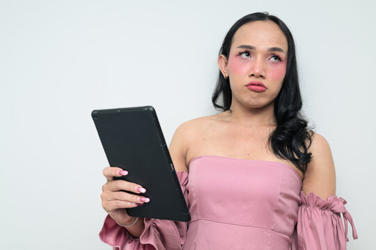 Bored young Thai transgender person against white background with digital tablet computer