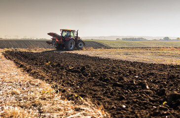 Tractor plowing field the land at sunset