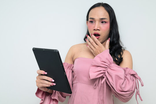 Shocked young Thai transgender person against white background with digital tablet computer