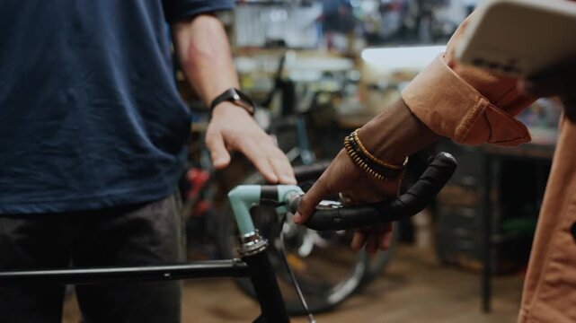 Unrecognizable man asking technician to check bicycle handlebar and brake lever in repair workshop