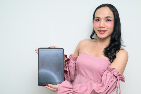 Portrait of a young Thai transgender person against white background with digital tablet computer