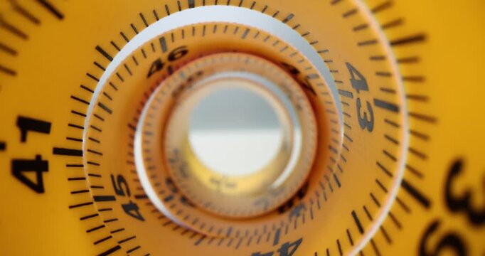 Orange measuring tape spiral tunnel represents relentless passage of length. Color tube of flexible ruler with black scale and digits on table