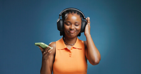 Headphones, smile and black woman with studio background for phone, music and playlist. Listening, audio tech and African female person with break for album, radio or song for rhythm and groove © Wess/peopleimages.com