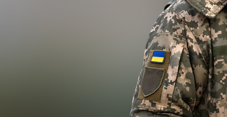 Ukrainian soldier in the army and flag, coat of arms with a golden trident on a military uniform background. Armed Forces of Ukraine.