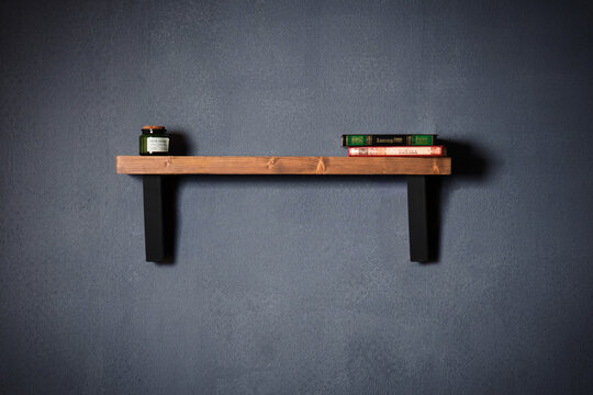 Modern wall shelf with design. Decorative wooden and metal shelf on a dark wall. Designer diamond-shaped wall shelf in loft style