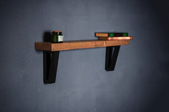 Modern wall shelf with design. Decorative wooden and metal shelf on a dark wall. Designer diamond-shaped wall shelf in loft style