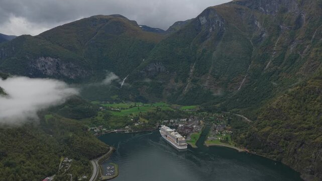 Top-down drone capture of Flam port and cruise ship surrounded by dramatic Norwegian nature