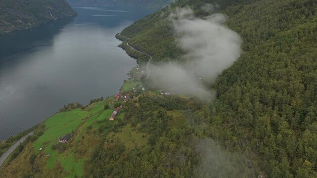 Drone view of Otternes bygdetun on fjord edge under dark clouds in western Norway