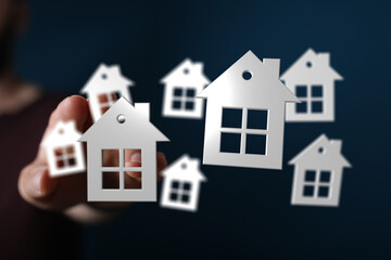 Hand holding multiple house symbols, illustrating concepts of home ownership, investment, and dreams. Ideal for real estate, finance, and future