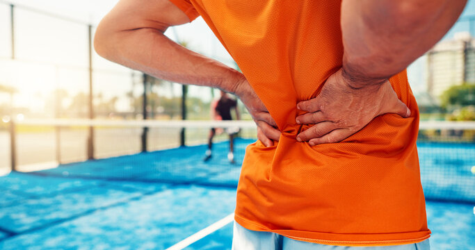Hands, person and back pain on tennis court for fitness, match accident and muscle sprain. Player, discomfort and joint strain of exercise mistake, inflammation and sports injury from tournament game