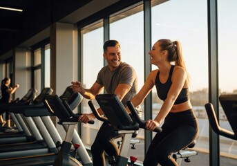 Happy couple working out together on stationary bikes at the gym