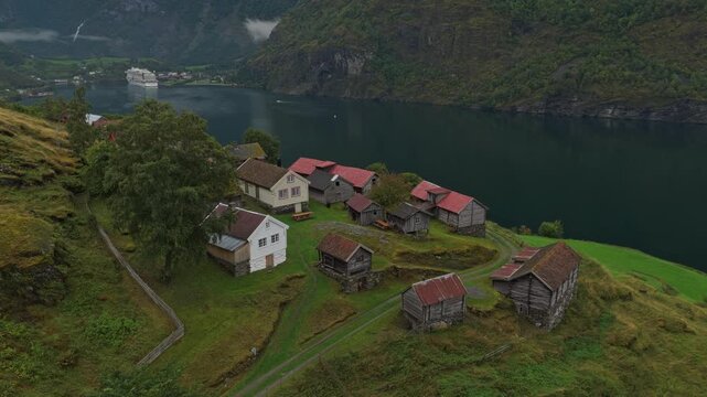 Old Norwegian farm village Otternes beside fjord in soft gray light, aerial view