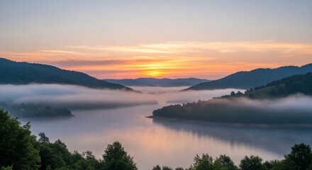 Fototapeta premium Serene sunrise over a misty lake surrounded by rolling, tree-covered hills, casting a warm, golden glow across the tranquil water.