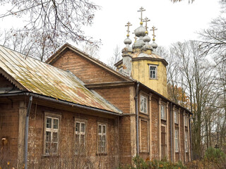 Abandoned wooden orthodox church with peeling paint, gilded cupolas and weathered crosses,...
