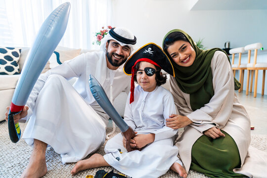 Emirati family playing with son in pirate costume at home - Powered by Adobe