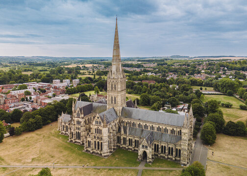 Salisbury UK: 27th July 2025: Salisbury Cathedral towers elegantly in an aerial view, showcasing its spires and intricate design amid the lush landscape of Salisbury, England