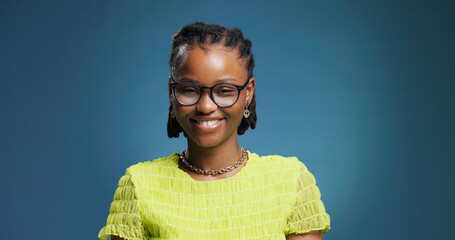 Portrait, woman or college student in studio with glasses for fashion degree, learning or education. Space, person or smile with eyewear for creative study, university or knowledge on blue background
