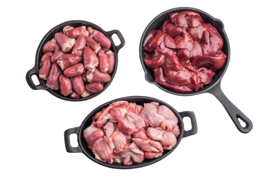 Raw chicken liver, gizzards, and hearts in black cast iron pans on white background. Fresh poultry offal cooking ingredients closeup.