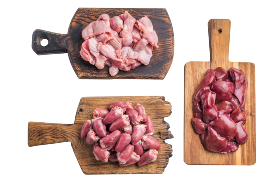 Raw poultry organs chicken hearts, liver, and gizzards on rustic wood boards, high protein ingredients for traditional cooking.