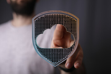 Hand pointing towards a cloud computing symbol within a shield, representing secure data protection and online