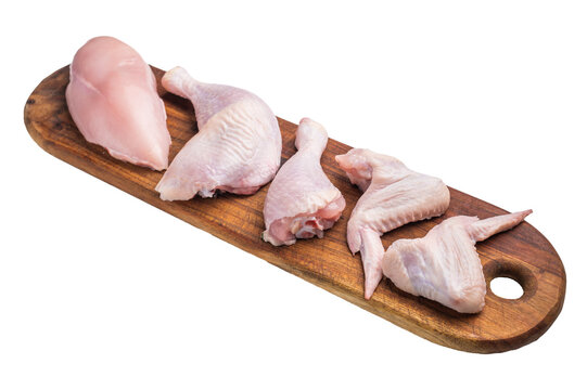A panoramic view of raw chicken cuts: boneless breast, leg quarter, drumstick, and wings, presented on a dark wooden cutting board.