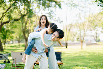 Joyful family playing together in a sunny green park. A candid outdoor moment full of love,...