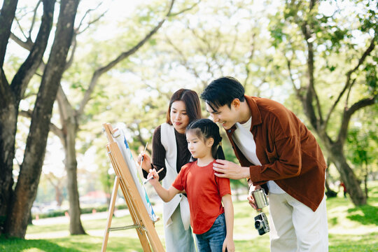 Happy family painting together outdoors in a sunny green park. A joyful lifestyle moment filled with creativity, learning, love, and togetherness.