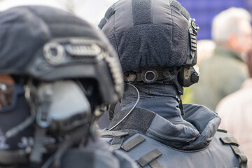 The police are among people in gear with a helmet and a connected communication cable.