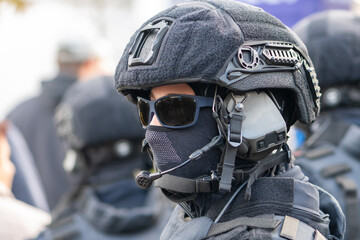 Fototapeta premium A policeman stands on the street wearing a helmet, glasses and a mask with a microphone connected.