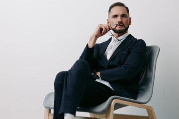 A professional man sits in a modern chair, exuding confidence and focus against an isolated colored background. The pose conveys contemplative emotion and poised professionalism.