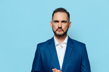 A focused business professional stands against a solid blue backdrop, conveying confidence, calm leadership, and decisive mindset in a corporate setting.