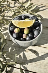 grey bowl with black olives with lemon slices on top