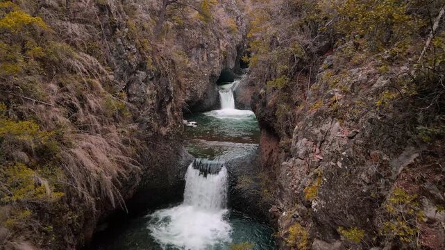 Forward drone aerial of multi-tiered waterfalls with turquoise pools, Siete Tazas National Park, &Ntilde;uble, Chile through narrow canyon slot