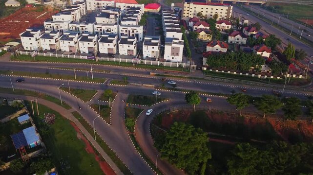 Jib down of a newly developed suburban neighborhood in the Gudu area in the city of Abuja, Nigeria on a sunny day. Cars driving over a busy road while the camera tilts up