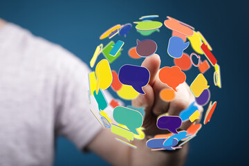 Abstract image of a hand interacting with a sphere composed of vibrant speech bubbles. Represents global communication, digital dialogue, and o