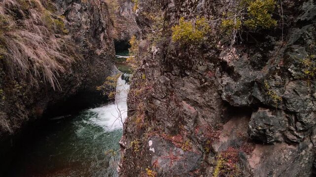 Orbiting revealing drone aerial of waterfall through narrow canyon slot, Siete Tazas National Park, &Ntilde;uble, Chile with rugged rock cliffs