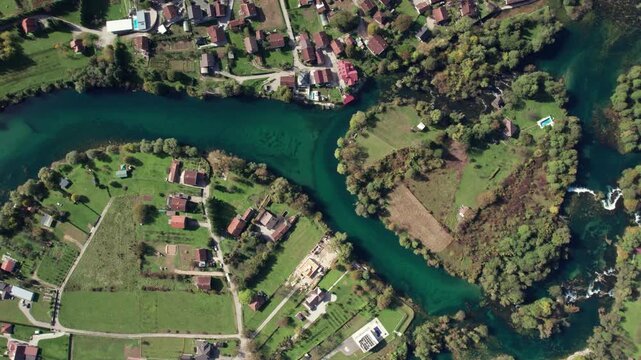 Aerial drone wide view showing the heart shaped bend of the Una River surrounded by nature and houses near Bihac, Bosnia and Herzegovina. Clear turquoise water and green fields visible from above