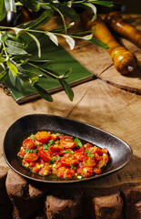 Fresh tomato dish served on rustic wooden table with greenery