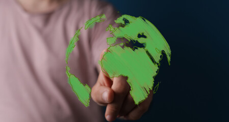 Conceptual image of a hand interacting with a glowing green Earth, representing global environmental efforts, sustainability, and digital connec