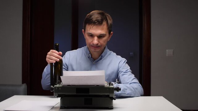 Man is taking a big swig from a dark bottle of alcohol, sitting at a desk with an old fashioned typewriter and a blank sheet of paper, depicting writer's block, stress, and lack of inspiration