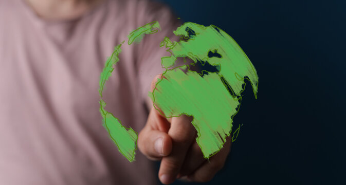 Conceptual image of a hand interacting with a glowing green Earth, representing global environmental efforts, sustainability, and digital connec