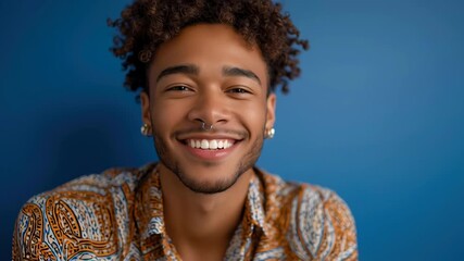 Young african male smiling in colorful shirt against blue background