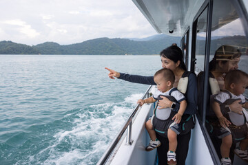 Naklejka premium Mother carrying baby in carrier on boat