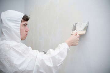 Man plastering wall with putty knife for home renovation
