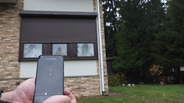 User's hands open Rolling Shutter Window using smart home mobile app and stop door mid-motion. High quality 4k footage