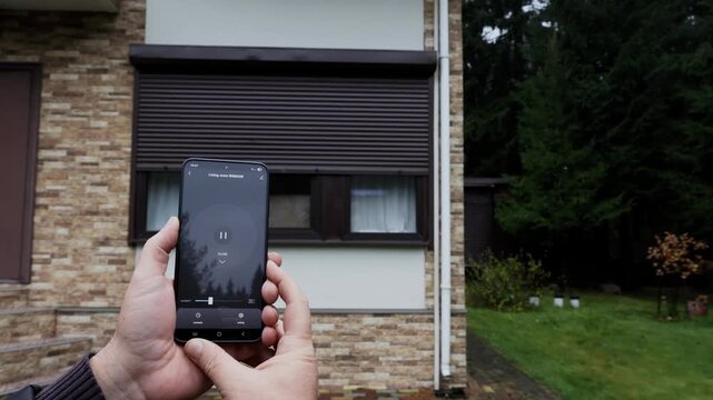 User's hands open Rolling Shutter Window using smart home mobile app and stop door mid-motion. High quality 4k footage
