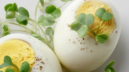 A pristine close-up shot of two perfectly halved hard-boiled eggs, artfully arranged on a clean white surface. The vibrant yellow yolks stand out against the firm, pure white protein, creating a visua - Powered by Adobe